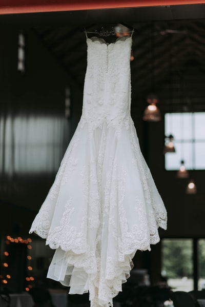 女人的白色露肩的婚纱挂在衣架上
